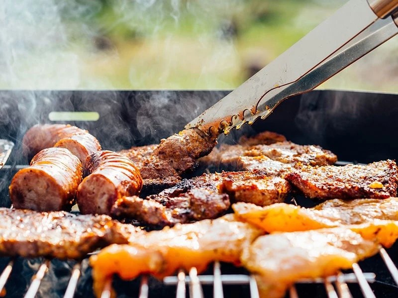 Grillen im Garten Würstchen und Koteletts auf dem Grill